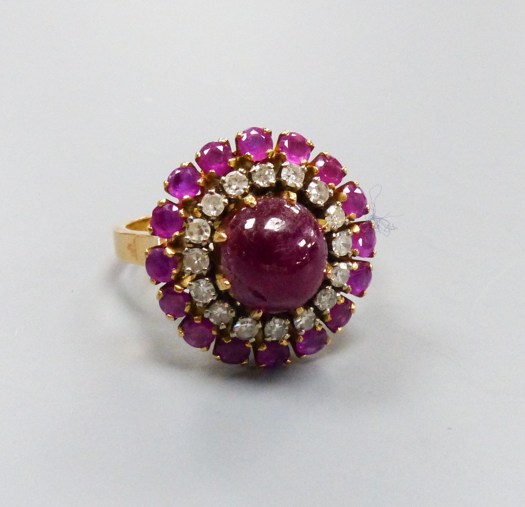 An Indian yellow metal, cabochon ruby and diamond cluster ring, size N, gross weight 8.3 grams, (central stone cracked).